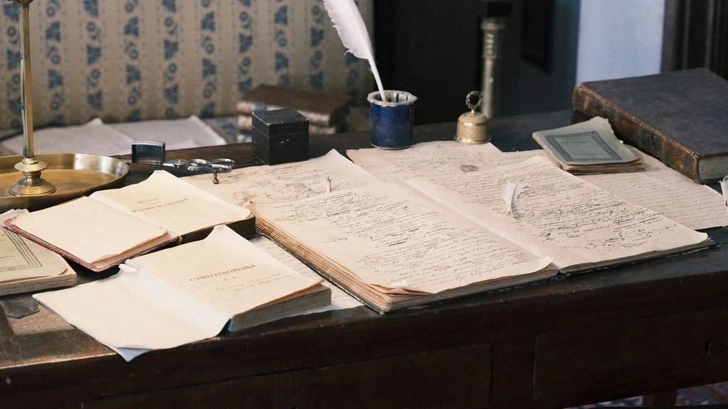 An editor's desk with a fountain pen resting on a galley proof and a small field microphone, photographed in warm sepia